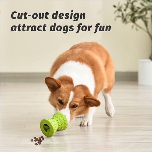 Corgi nosing spilled kibble from the green rubber chew toy's hollow cut-out on a wood floor